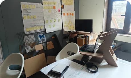 Sidharth's desk with a monitor, chair and pinboard of notes